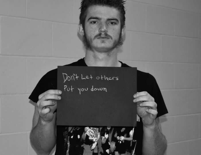 Young student holding a sign that says "Don't let others put you down."