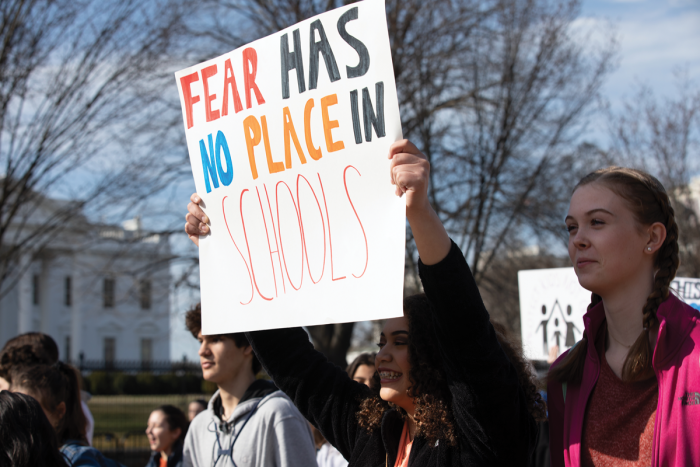 Adult holding sign that reads "Fear has no place in schools."