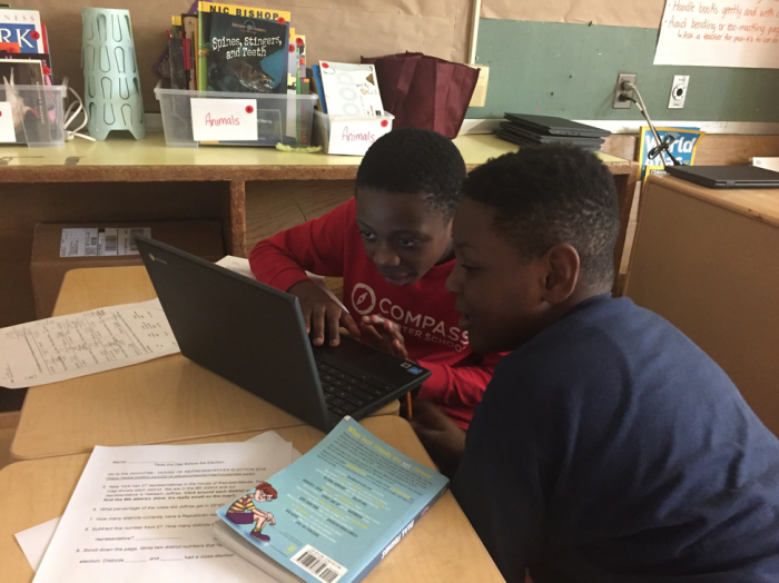 Two young students sitting and working together in front of a computer.