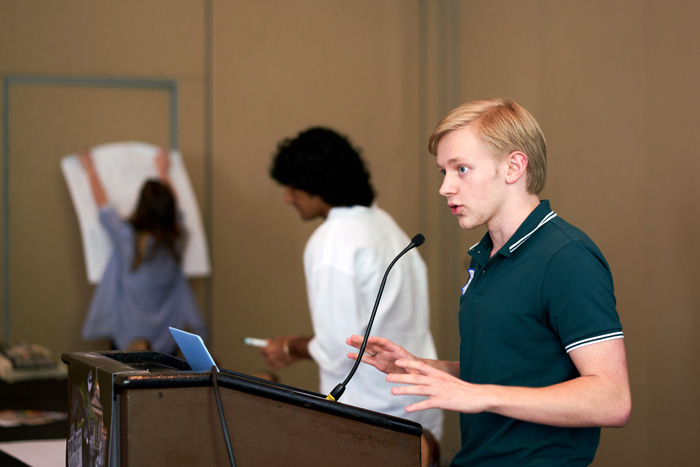 Julian Fortuna (right) at the podium during a JADE event while Koan Roy-Meighoo (center) engages in the work.