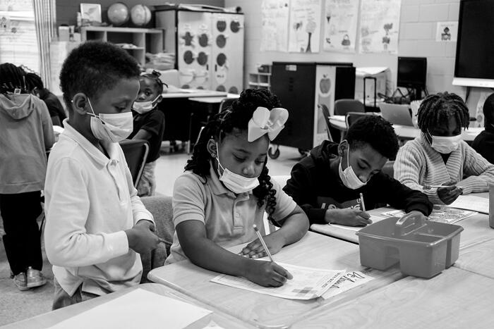 Photograph of masked children in a classroom working on a project.