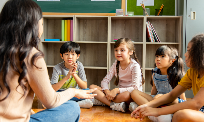 Four children sitting in a circle with a teacher.