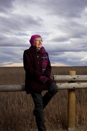 Teacher sits on a fencepost in an open field