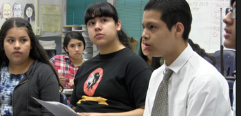 Group of students looking on as a classmate talks to someone outside of the photo.